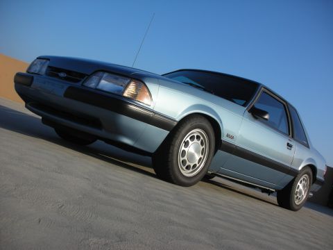 1990 Ford Mustang - Light blue 1990 Ford Mustang coupe with black trim parked outdoors.