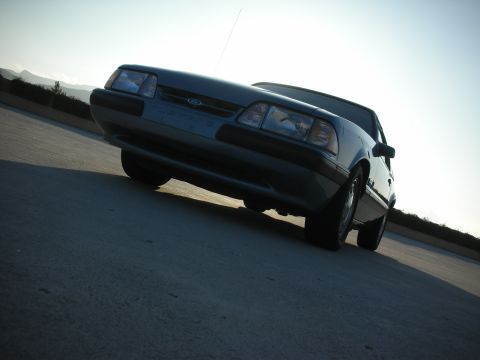 1990 Ford Mustang - This 1990 Ford Mustang convertible is captured from a low angle, highlighting its front end against a bright sky.