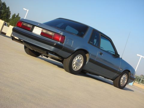 1990 Ford Mustang - 1990 Ford Mustang coupe parked outdoors under a clear sky.