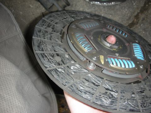 1990 Ford Mustang - A worn clutch disc, likely needing replacement, is held for inspection.
