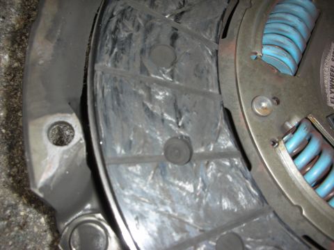 1990 Ford Mustang - Close-up of a worn clutch disc and pressure plate assembly, showing mechanical components.