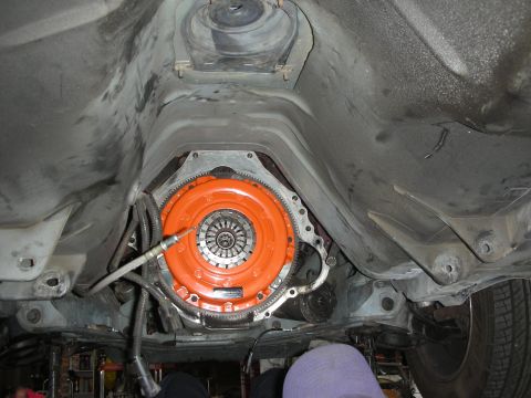 1990 Ford Mustang - Close-up of a car's transmission and clutch assembly, viewed from below.