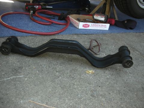 1990 Ford Mustang - A black control arm lies on the ground next to an air impact wrench and red hose.