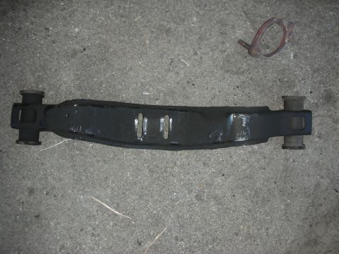 1990 Ford Mustang - Automotive suspension part with rubber bushings shown on concrete. No year or vehicle identification visible.
