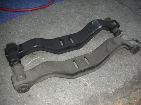 1990 Ford Mustang - Comparison of two automotive control arms, one appearing newer or repainted.