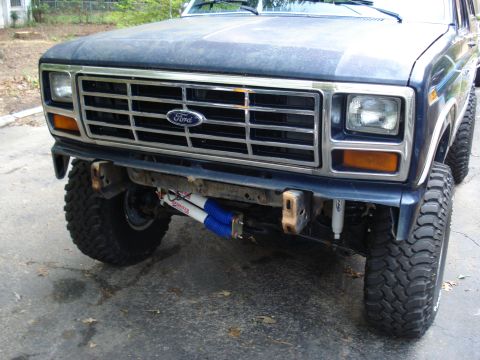 1984 Ford Bronco - Front view of a dark blue Ford Bronco, showing its grille and suspension modifications.