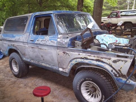 1978 Ford Bronco - This weathered Ford Bronco is undergoing restoration, with its hood removed to expose the engine bay.