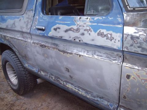 1978 Ford Bronco - Side view of a 1978 Ford Bronco undergoing bodywork, showing extensive primer and filler application.