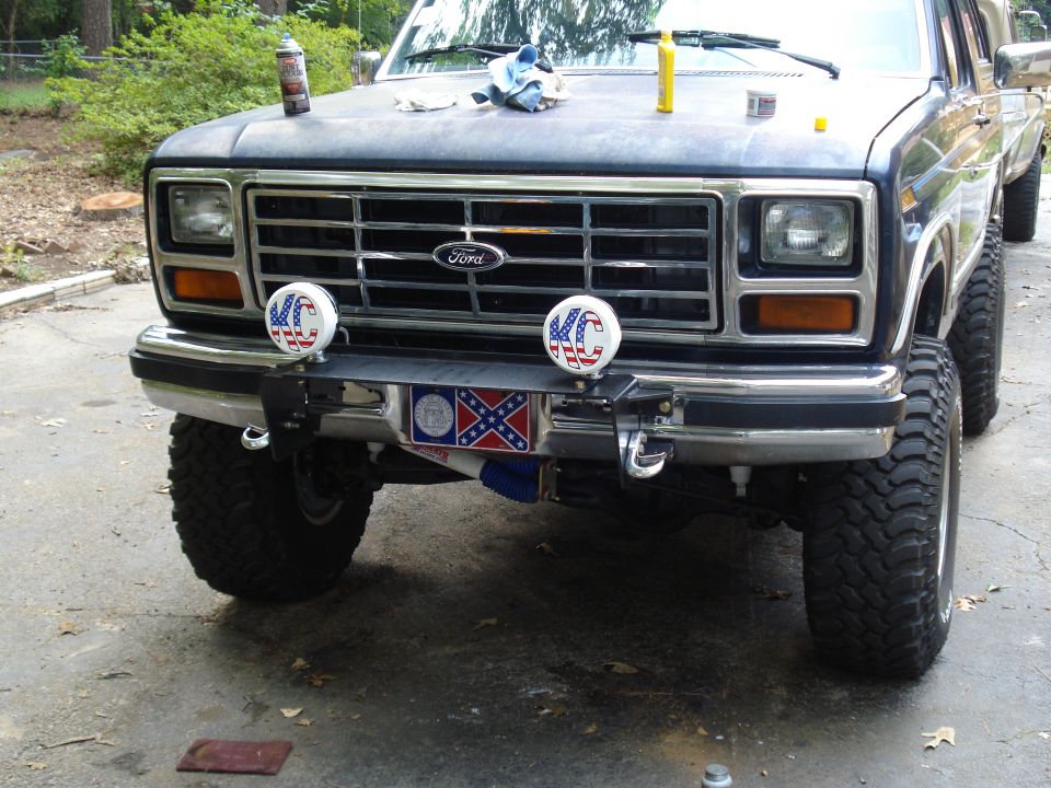 Front view of a dark blue Ford truck with KC lights and a Confederate flag plate