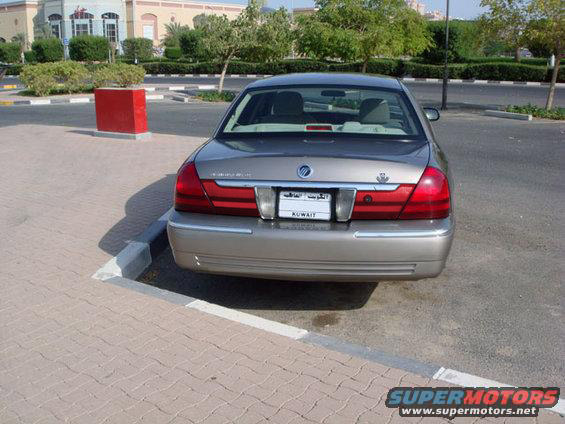 Rear view of tan Mercury Grand Marquis sedan with Kuwait plate in a paved lot