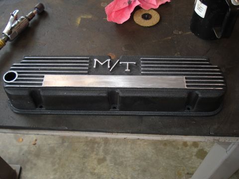 1984 Ford Bronco - A black engine valve cover with silver M/T lettering and decorative fins sits on a workbench next to a tool.