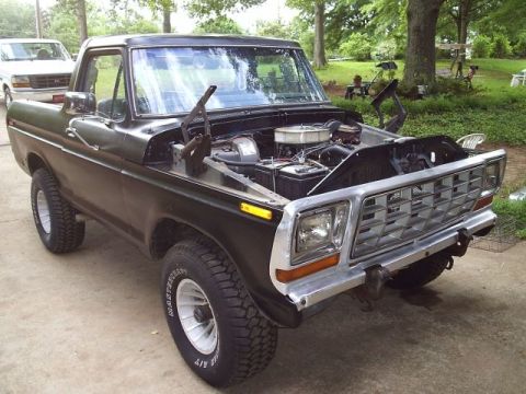 1978 Ford Bronco - 3/4 front view of a dark green late-'70s Ford Bronco-style SUV in a driveway with the hood removed, exposing a chrome-topped air cleaner an…