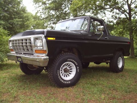 1978 Ford Bronco - A flat-black early Ford Bronco, front three-quarter view, with chrome grille and front bumper, white slotted wheels and Mastercraft Courier…