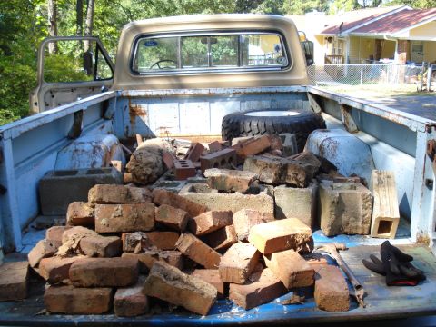 1967 Ford F-250 - Rear view of a 1967 Ford F-250 pickup truck bed filled with construction debris, including bricks and cinder blocks.