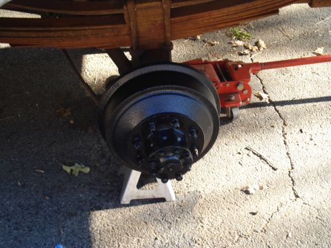 1967 Ford F-250 - The rear axle drum brake assembly of a 1967 Ford F-250 is shown, supported by a jack stand and a red hydraulic jack.