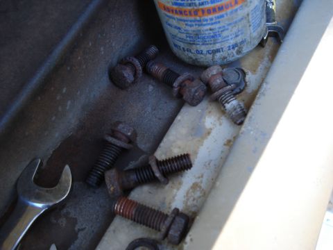 1967 Ford F-250 - A collection of rusty bolts and a wrench are visible in a metal tray, alongside a can of lubricant.