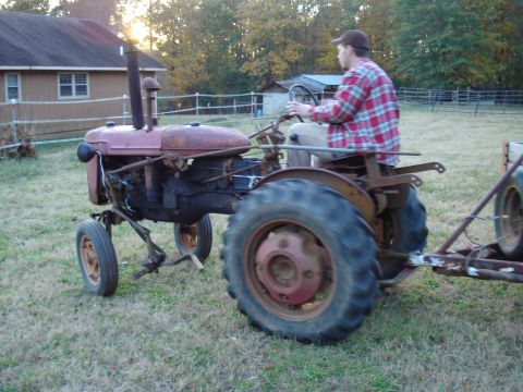 1967 Ford F-250 - A man operates a vintage tractor, pulling a small trailer across a grassy field.
