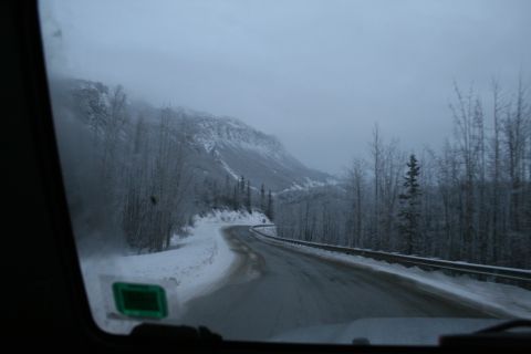2003 Jeep TJ - View from inside a vehicle driving on a snow-covered road through a mountainous, wooded area.