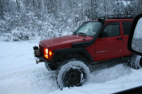 2003 Jeep TJ - Red Jeep Cherokee XJ navigates a snowy trail with its snorkel engaged.