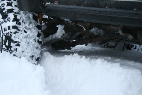 2003 Jeep TJ - A 2003 Jeep TJ navigates through deep snow, its aggressive tires digging in for traction.