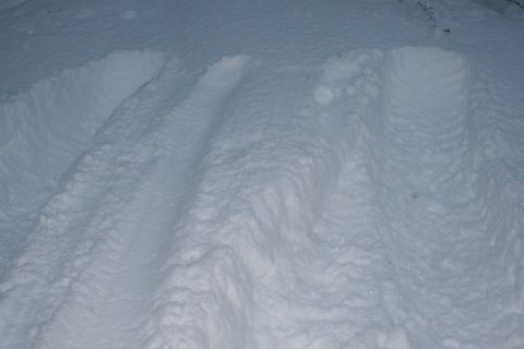 2003 Jeep TJ - The image shows tire tracks imprinted in a thick layer of snow, suggesting recent vehicle passage.