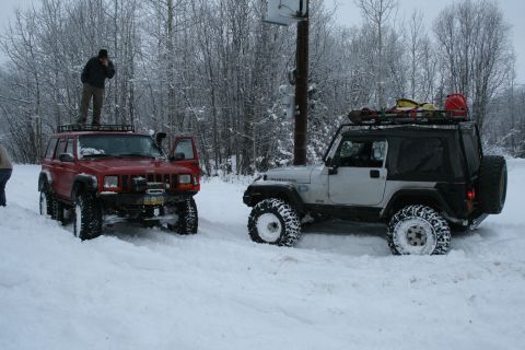 2003 Jeep TJ - Two Jeeps, including a white 2003 Jeep TJ, are parked in deep snow with trees in the background.