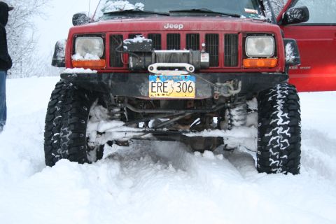 2003 Jeep TJ - A red Jeep Cherokee XJ is stuck in deep snow, its front end equipped with a winch.