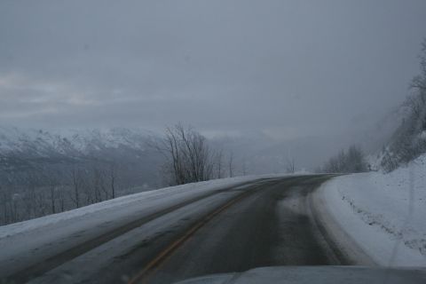 2003 Jeep TJ - A winding road through a snowy mountain landscape under a cloudy sky.