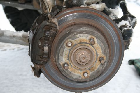 2003 Jeep TJ - Front brake assembly of a Jeep TJ, showing the rotor and caliper in snowy conditions.