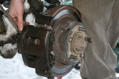 2003 Jeep TJ - A person is holding a vehicle's brake assembly, which is covered in snow.