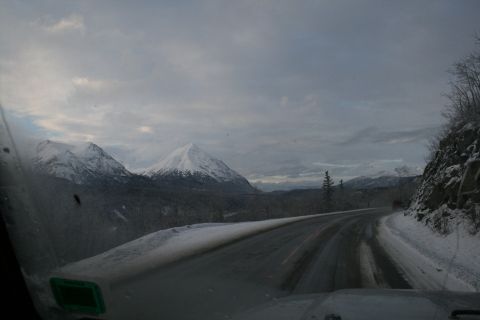 2003 Jeep TJ - Driving on a snowy mountain road with snow-capped peaks under a cloudy sky.