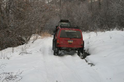 2003 Jeep TJ - Two Jeeps navigate a snow-covered trail through a wooded area.