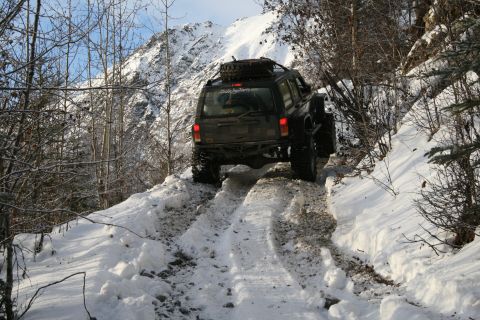 2003 Jeep TJ - Jeep Cherokee XJ navigates a challenging snowy mountain path, its off-road capabilities.