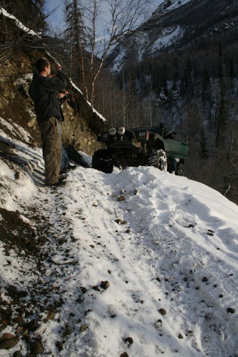 2003 Jeep TJ - Two off-road vehicles on a snowy mountain path, with a person observing the scene.