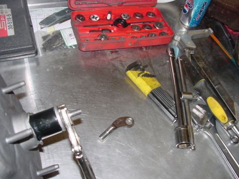 1979 Ford Bronco - Various tools and a car part are laid out on a metal workbench, suggesting a repair or maintenance task.