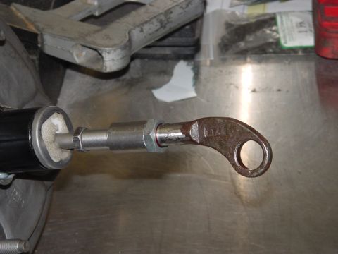 1979 Ford Bronco - Rusty brake caliper part with hex nut and black cylinder on a metal workbench.
