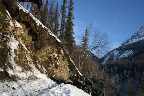 2003 Jeep TJ - 2003 Jeep TJ on a snowy mountain road, with a steep, rocky embankment to the left.