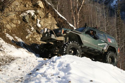 2003 Jeep TJ - This modified Jeep Cherokee XJ is navigating a challenging snowy incline.