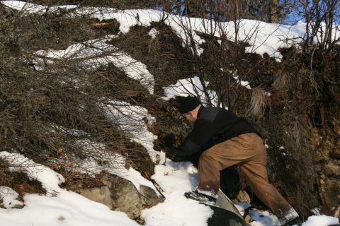 2003 Jeep TJ - A person is seen on a snowy hillside, surrounded by dry brush and rocks under a clear sky.