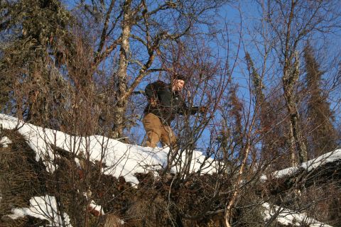 2003 Jeep TJ - A person navigates a snow-covered hillside surrounded by bare trees under a clear blue sky.