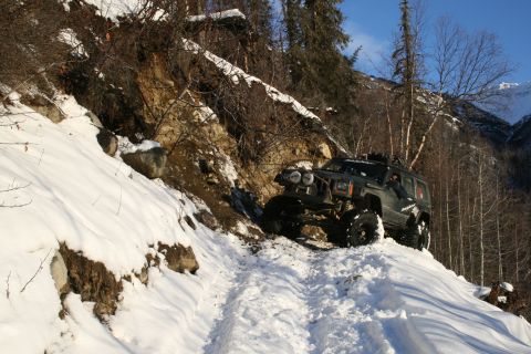 2003 Jeep TJ - Modified Jeep Cherokee XJ navigates a challenging snowy path on a steep incline.