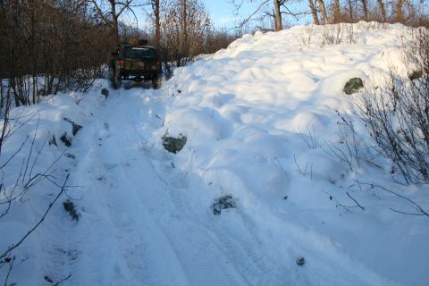 2003 Jeep TJ - A Jeep navigates a snow-covered path through a wooded area.
