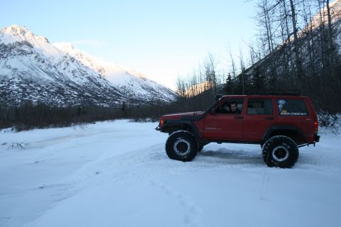 2003 Jeep TJ - Red Jeep Cherokee XJ navigates a snowy mountain landscape.