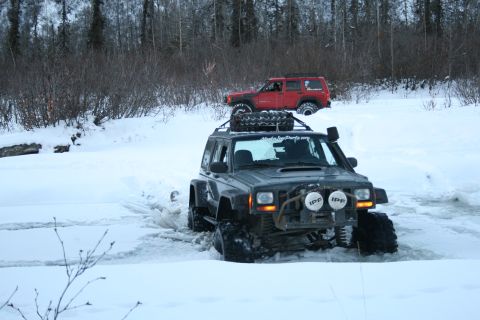 2003 Jeep TJ - Two off-road Jeeps navigate a snowy landscape, one following the other.