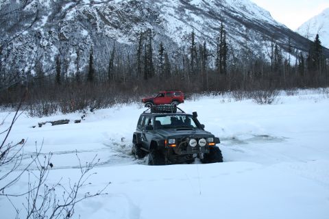 2003 Jeep TJ - Two Jeep SUVs navigate a snow-covered trail with a mountain in the background.