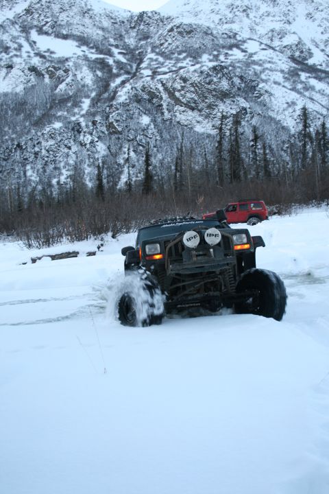 2003 Jeep TJ - Modified Jeep Wrangler TJ navigating a snowy terrain, with another Jeep visible behind it.
