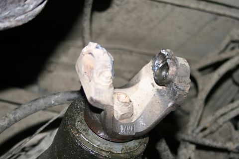 2003 Jeep TJ - Close-up view of a damaged driveshaft universal joint, showing a bent yoke and a worn bearing cap.