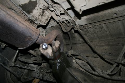 2003 Jeep TJ - Close-up view of the undercarriage, focusing on the rusted exhaust system and suspension parts.