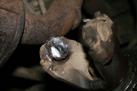 2003 Jeep TJ - Close-up of a damaged universal joint, showing significant metal deformation and debris.