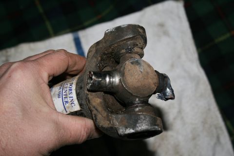 2003 Jeep TJ - A damaged driveshaft universal joint is held by a hand, showing wear and tear from use.